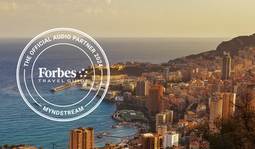 Monaco coastline with the Forbes Travel Guide Official Audio Partner badge